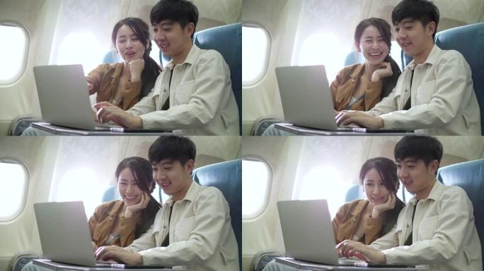 甜蜜的夫妇使用笔记本电脑在飞机上娱乐