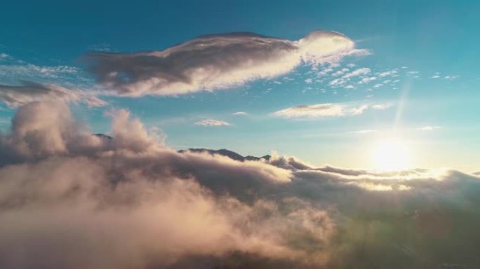 无人机摄像机在日落时穿越中亚雪山上方的云层拍摄。