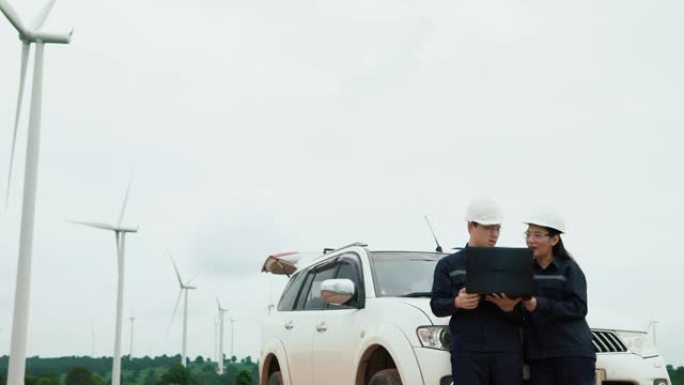 两名维修工程师在风力涡轮机附近统一使用笔记本电脑支架生态能源工业动力风车领域可再生