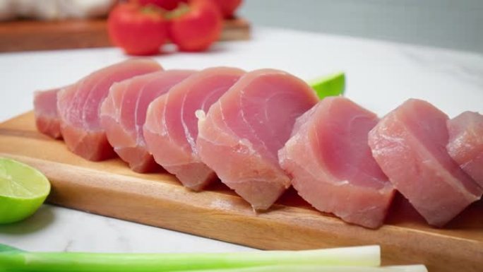 将切成薄片的生金枪鱼黄鳍放在桌子上，上面放着4K的蔬菜和蔬菜。