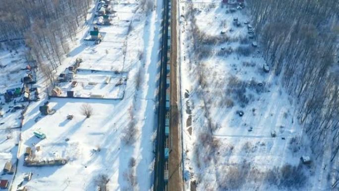 平静的风景 -- 冬季的乡村景象。轨道交通的主题。火车在居民楼附近缓慢行驶。航空勘测。