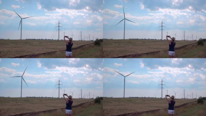 一个女孩在智能手机上拍摄风力发电机