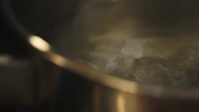 在厨房的燃气灶上关闭带有烟雾的锅开水。