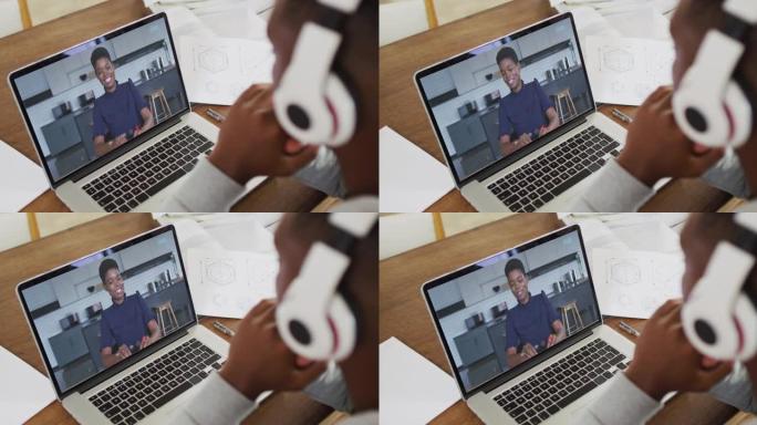 非裔美国男大学生在家里用笔记本电脑进行视频通话时拿着笔记