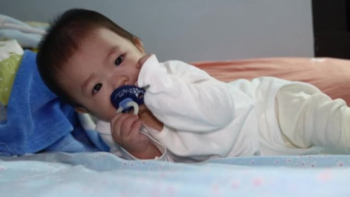 亚洲华裔男婴躺在床上穿着白色睡衣的当地生活方式镜头