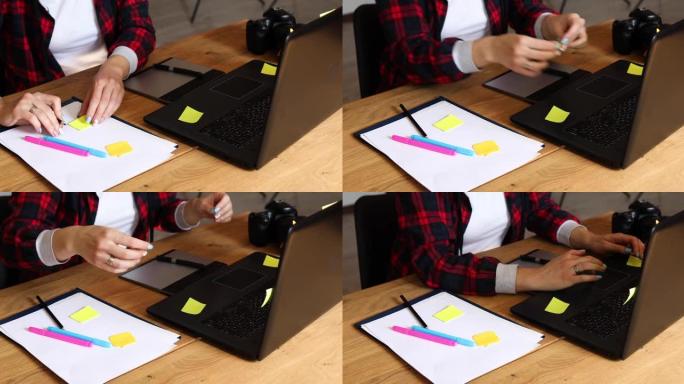 在创意办公室工作的摄影师女性做笔记，并在笔记本电脑上润饰照片