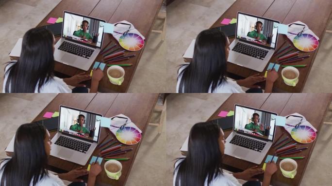 非裔美国女教师在笔记本电脑上与男孩进行视频通话时在备忘录笔记上写作