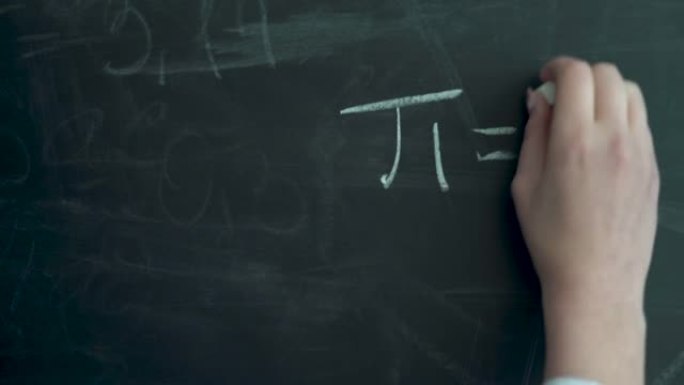 写圆周率。在黑板上写下数字pi。一只女性用白色粉笔写字。