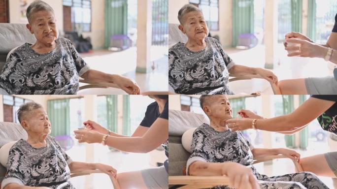 亚洲妇女照顾奶奶在家给残疾的亚洲人服药奶奶