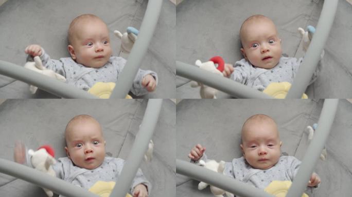 可爱的男婴躺在婴儿活动健身房游戏垫玩悬挂玩具，婴儿感官发育，2个月大的新生婴儿在客厅地板上