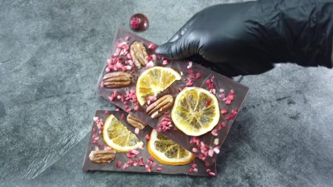 手工巧克力棒被展示在你的手中。特写奢华手工巧克力配香料、干浆果和坚果。