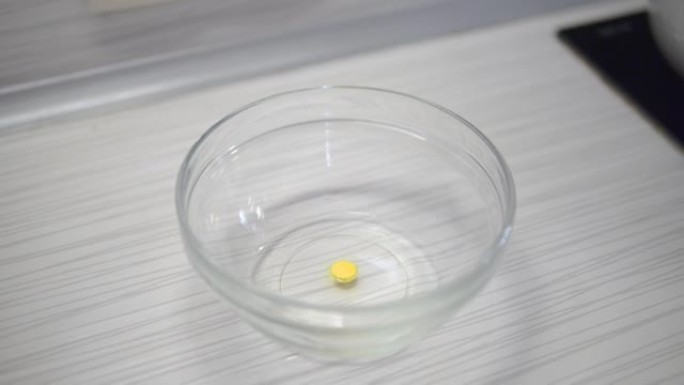 将黄色药片浸入一盘液体中。复活节彩蛋涂料