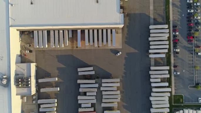 汽车在一个大仓库的卡车停车场上行驶。空中鸟眼正上方。带有平移相机运动的无人机制作的镜头。