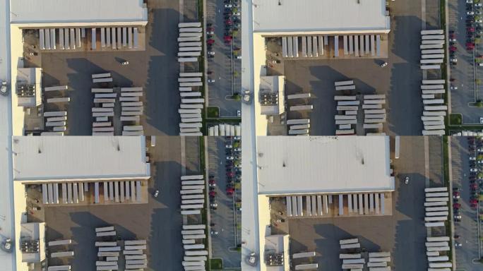 汽车在一个大仓库的卡车停车场上行驶。空中鸟眼正上方。带有平移相机运动的无人机制作的镜头。