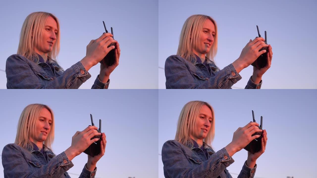日落特写时，一名妇女的手握着无人机的遥控器。