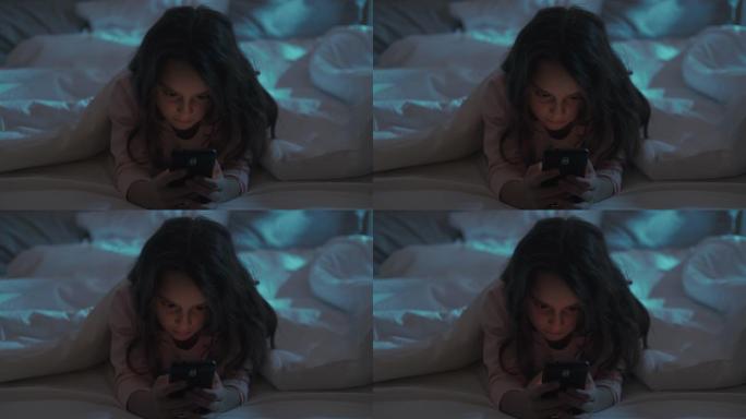 小玩意夜晚疲惫的小女孩在床上用手机