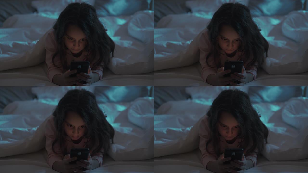 小玩意夜晚疲惫的小女孩在床上用手机