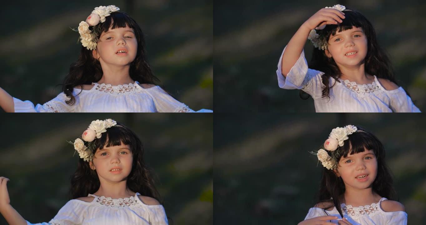 一个白人学龄前小女孩的特写肖像，棕色长发，蓝色的眼睛在花环上跳舞，在自然背景上微笑。4k 50 fp