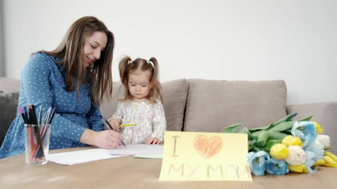 小女孩与怀孕的母亲在家里画画