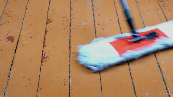 柔软的拖把清洁和清洗房间里的旧木地板。清洁和消毒。例行家务。