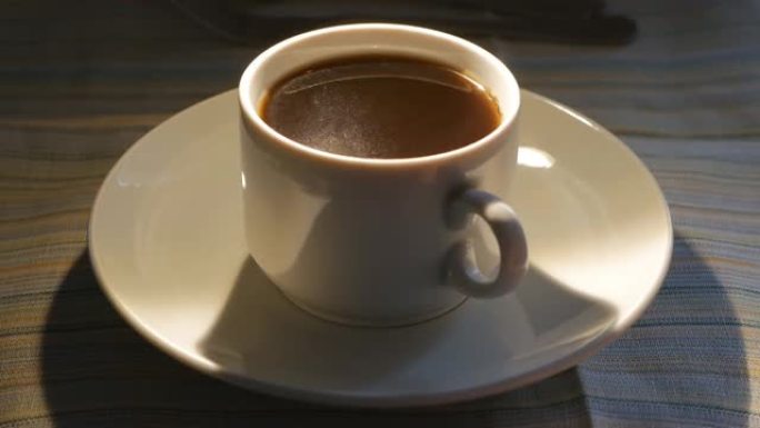 桌子上白色杯子里的黑咖啡因地震而颤抖