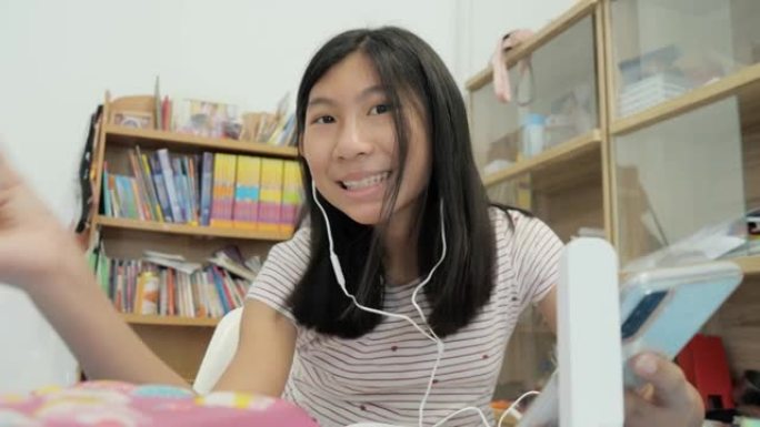 亚洲女学生在新型冠状病毒肺炎期间通过智能手机在家在线学习，社交距离生活方式概念。