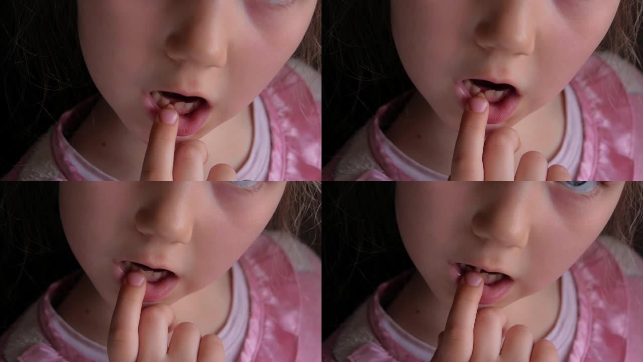 害怕的小女孩6-7岁失去了较低的乳牙。可爱的学龄前儿童摇晃着牙齿，微笑着。4k镜头黑暗背景。