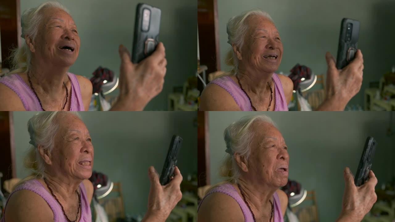 快乐的亚洲高级女性在家中使用智能手机vdo呼叫检疫的电影拍摄。