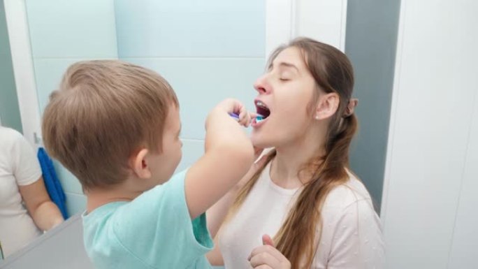 蹒跚学步的小男孩在浴室为母亲刷牙和清洁牙齿