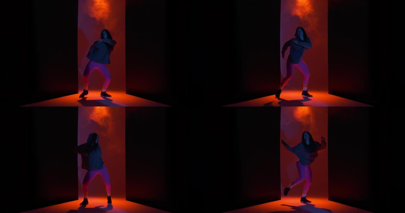 跳舞的酷女孩在工作室里用烟雾在五颜六色的灯光下表演自由式舞蹈。现代生活方式，霹雳舞