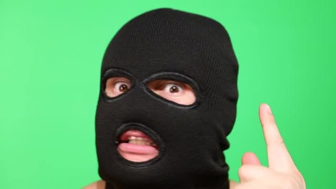 戴着面具的可怕小偷或强盗看着相机。