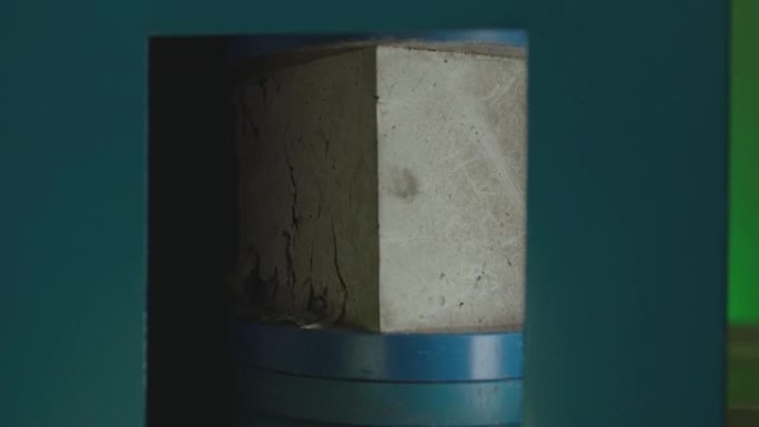 混凝土块在高压下断裂。液压机正在对混凝土制成的立方体产生压力。强度测试。混凝土立方体抗压强度试验。在