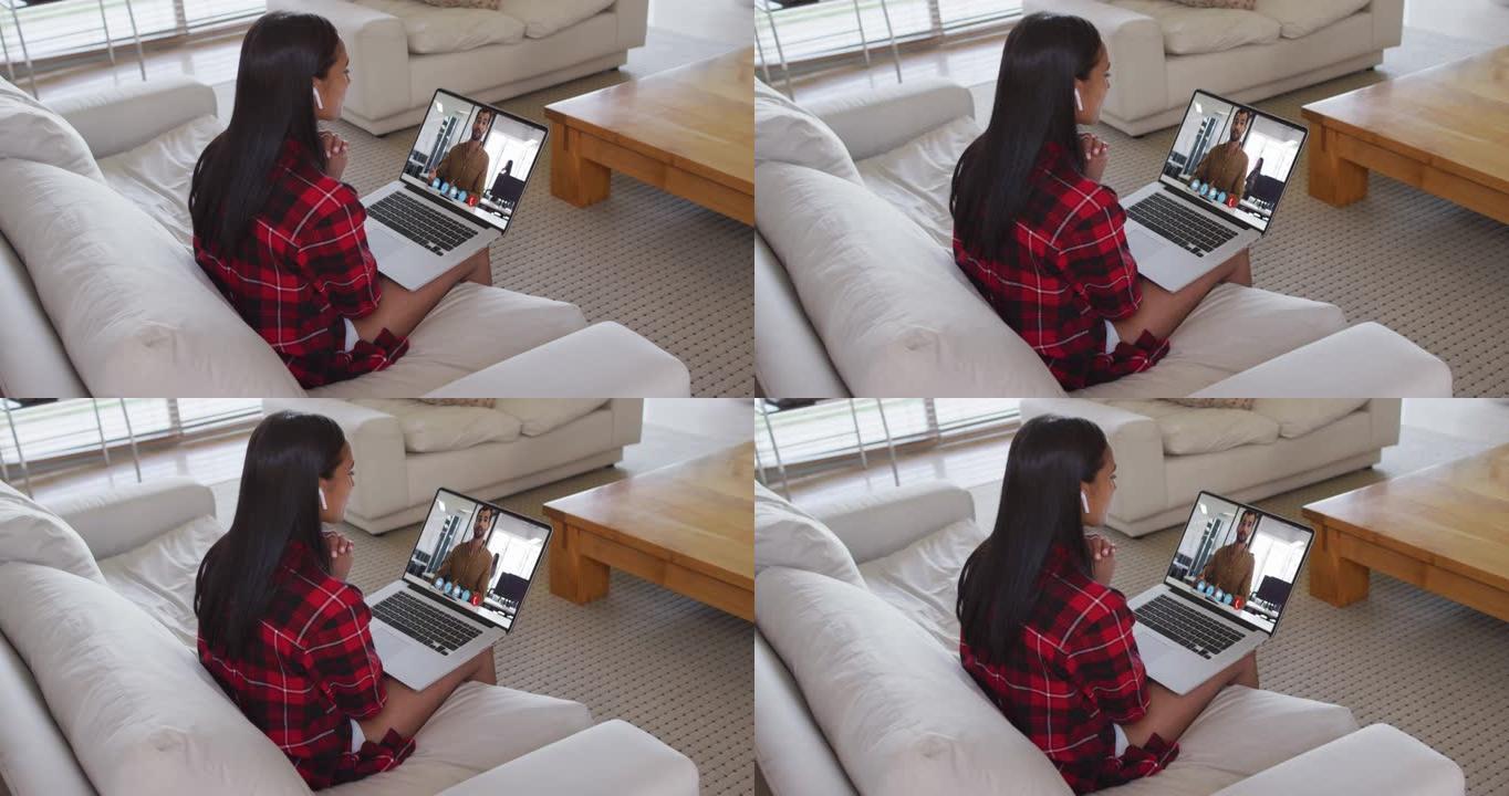 混血女商人坐在沙发上，用笔记本电脑与男同事进行视频通话