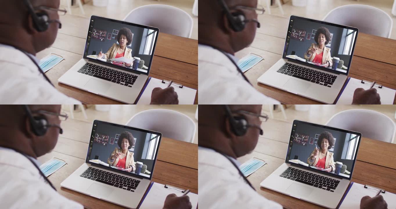 非裔美国商人坐在办公桌前，使用笔记本电脑与女同事进行视频通话