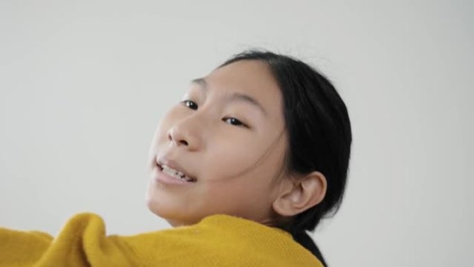 快乐的亚洲女孩穿着黄色毛衣跳舞和摇晃马拉卡斯与灰色背景，生活理念。