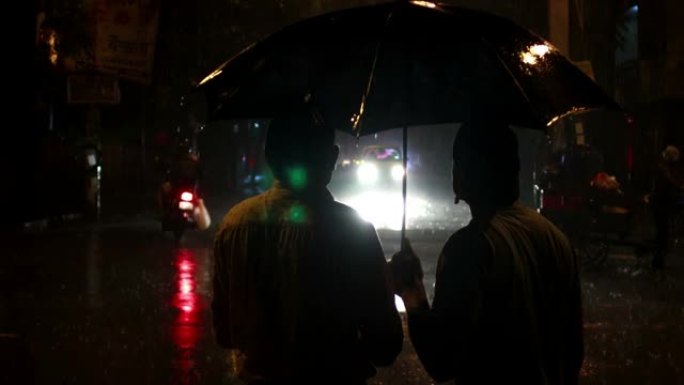 两个男人拿着雨伞在雨夜里聊天