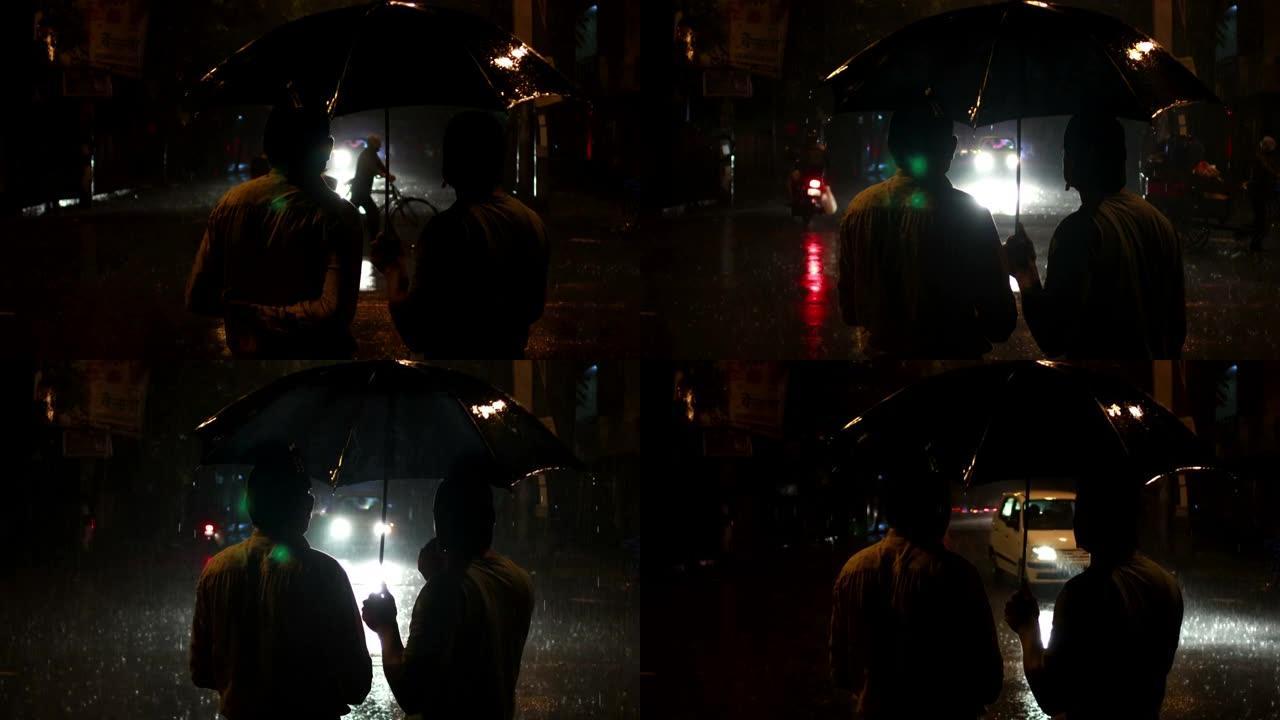 两个男人拿着雨伞在雨夜里聊天