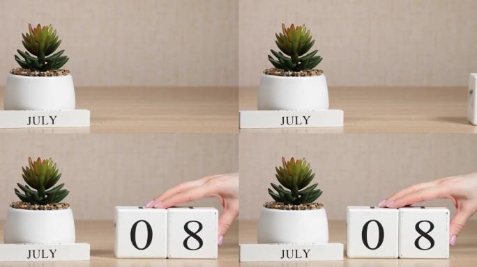 木制日历对7月8日来说是一个重要的事件，女人的手在日历上设置日期。夏季。