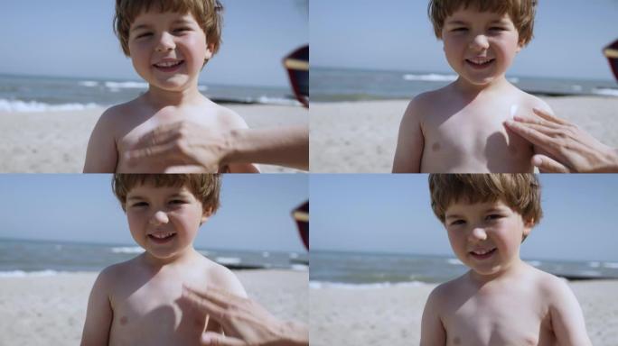 妈妈给孩子涂防晒霜。妈妈在海滩上给身体儿子涂防晒霜。母亲为孩子在海里洗澡做准备。海滩防晒快乐的家庭。