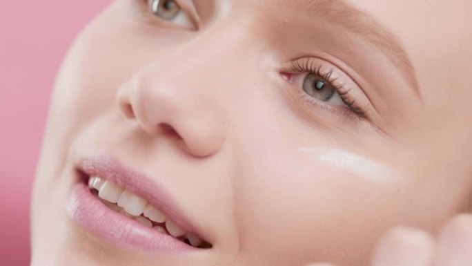 女性护肤品模特在相机上使用面带微笑的眼霜