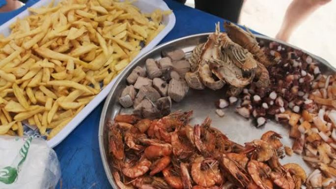 海滩上的一盘异国海鲜虾，鱿鱼，章鱼，金枪鱼和薯条