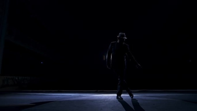 穿着经典帽子和西装的男人的剪影在经典剧院的舞台上跳舞。舞台上的暗光。概念视频。