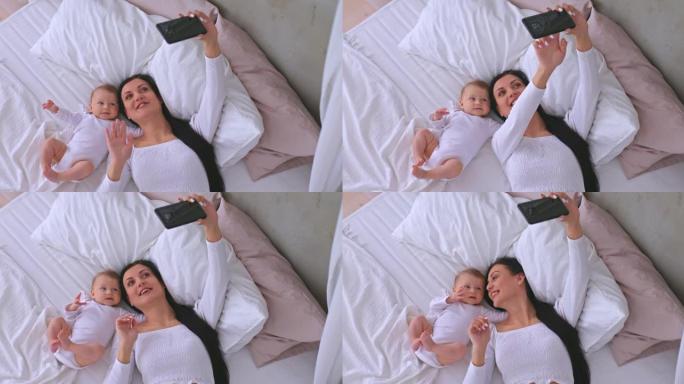 孩子和妈妈躺在床上，妈妈用手机通过视频交流打招呼。Skype聊天，妈妈挥挥手并进行视频通话。4k，普