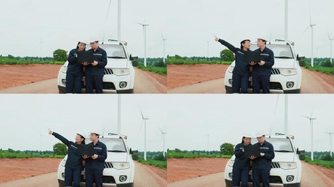 两名维修工程师在风力涡轮机附近统一使用笔记本电脑支架生态能源工业动力风车领域可再生