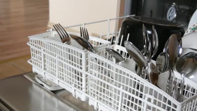 开放式洗碗机中干净闪亮的勺子和叉子的特写视图