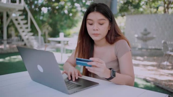 美丽微笑的年轻亚洲女性通过智能手机上的移动应用程序管理网上银行，并在喝杯咖啡，放松和享受下午的时光的