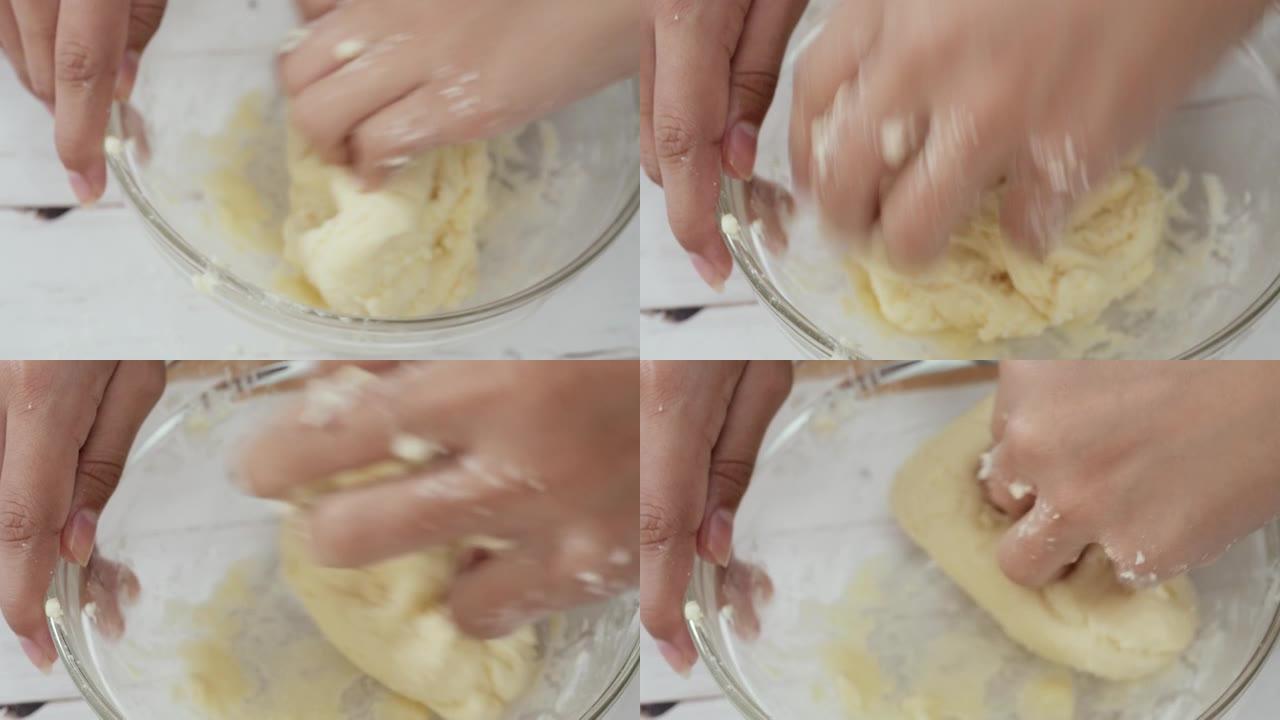 孩子的手在桌子上的搅拌碗中脱粒面粉，制作面包。