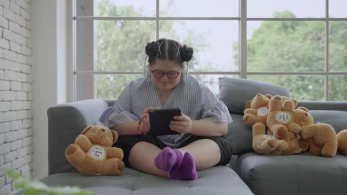 患有唐氏综合症的年轻亚洲女孩独自在房间里玩平板电脑