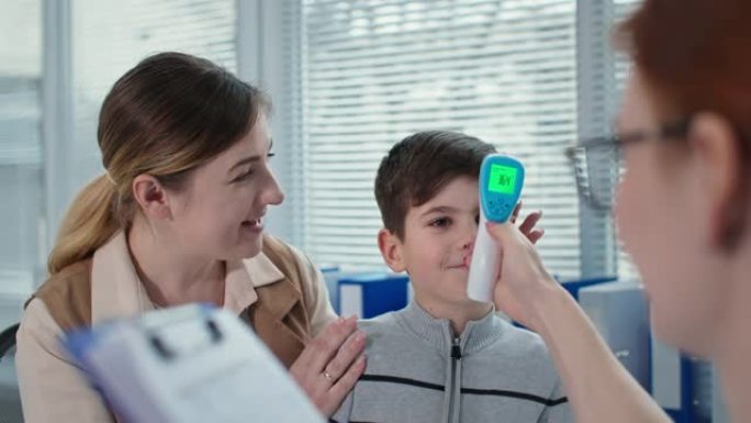 儿童保健，儿科医生用非接触式温度计测量小病人的体温，然后在剪贴板上做笔记