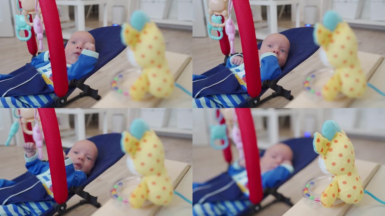 婴儿躺在婴儿摇椅上，为新生儿准备的色彩鲜艳的玩具拨浪鼓。